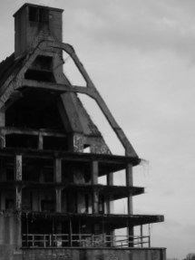 Schwarz-Weiß-Bild eines typischen Hafen-Speicherhauses, das teilweise nur noch als Stahlbetongerüst erhalten ist und so Blicke in sein Inneres gestattet.